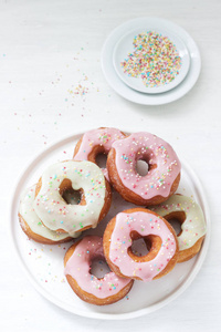 自制甜甜圈装饰彩色糖霜和彩色糖在一个轻的背景。 选择性聚焦。