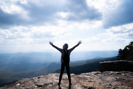 一个人站在岩石山上，眺望美丽的自然景色和美丽的蓝天