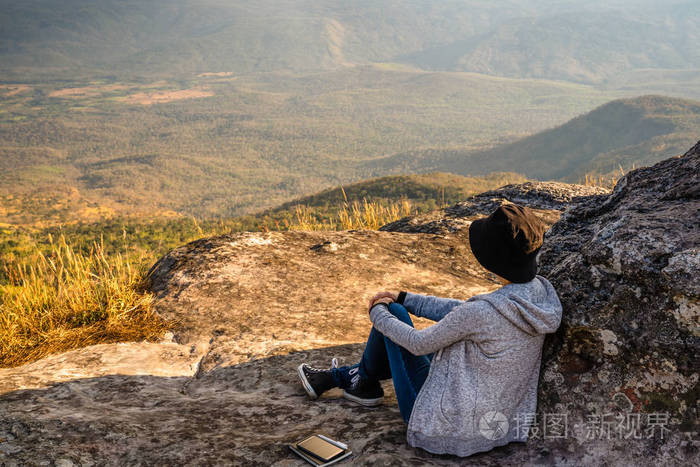 一个女人坐在岩石山上,眺望美丽的自然景色和美丽的蓝天