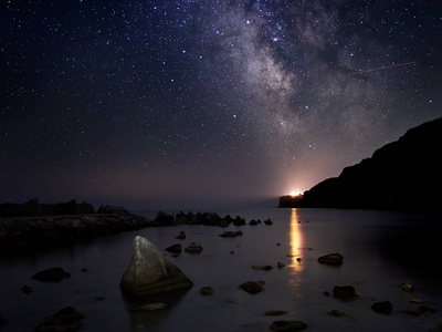 在岩石悬崖和海夜景观上令人叹为观止的充满活力的银河形象