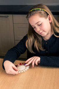 可爱的10岁白种人女孩的肖像选择她的指甲油在家坐在厨房的桌子垂直