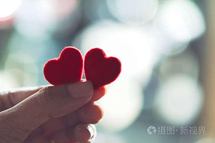 女性双手抱着一对红心选择性聚焦