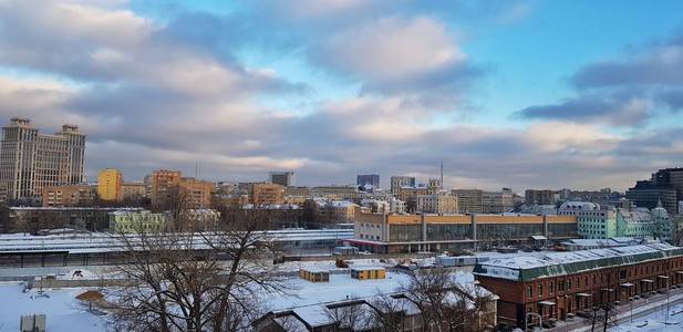 在莫斯科的黎明，房子和美丽的城市日出反射在高耸的窗户和摩天大楼的窗户上，在一个寒冷的冬天的早晨，明亮的天空云和工厂管道中的烟雾