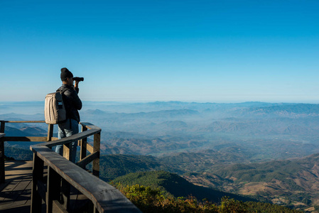 专业摄影师用相机拍摄山上旅游背包的风景照片照片