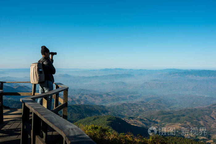 专业摄影师用相机拍摄山上旅游背包的风景照片