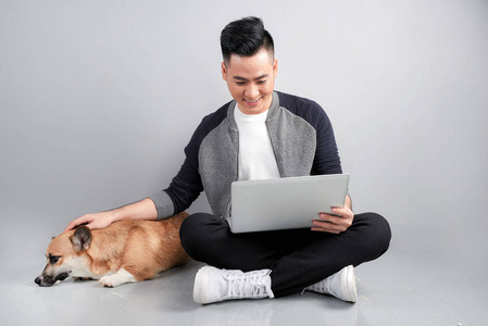 英俊的年轻商人和他的狗坐在地板上时使用笔记本电脑