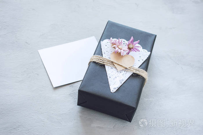 情人节模型。 工艺礼品盒空白卡。 黑色纸现盒与心花边餐巾黄麻绳灰色水泥背景。 爱情浪漫手工制作