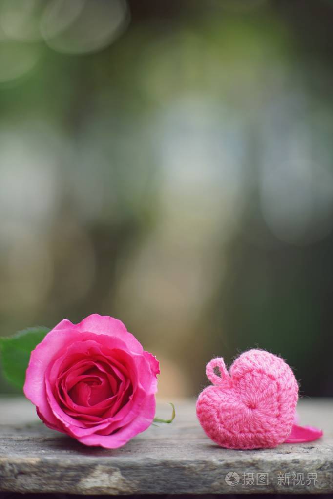 迷你小指心和单一优雅的粉红色玫瑰花装饰花瓣在木桌背景甜蜜情人节