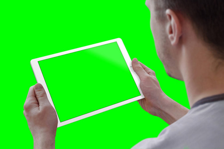 人持平板在水平位置。从肩膀上看。独立的屏幕模拟，背景绿色的视频编辑。