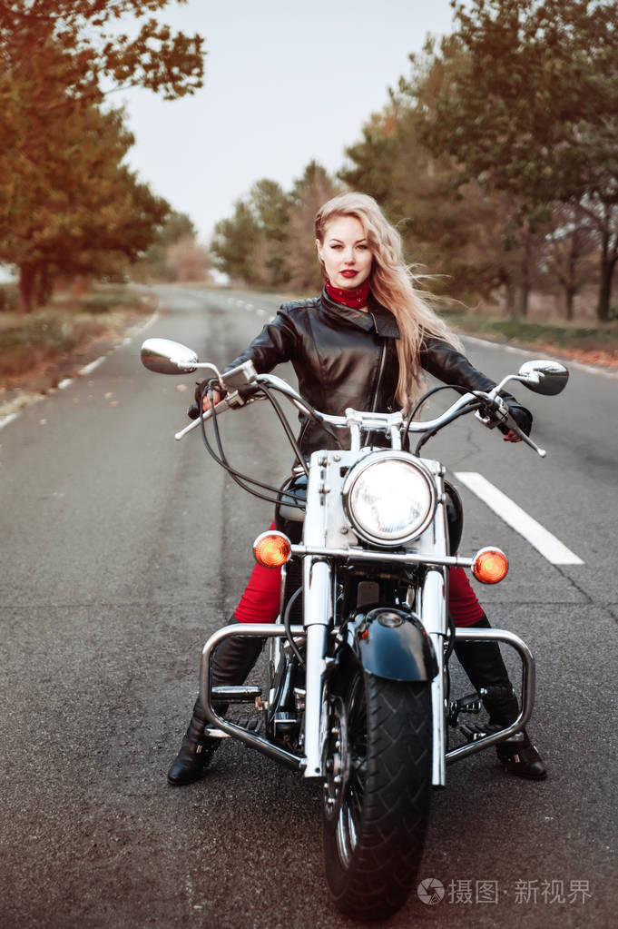 漂亮的骑摩托车的女人在马路上摆着摩托车在户外