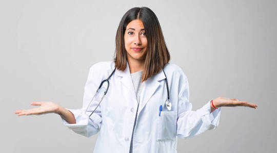 带有听诊器的女性医生在举起双手和双肩时有疑惑和困惑的面部表情照片