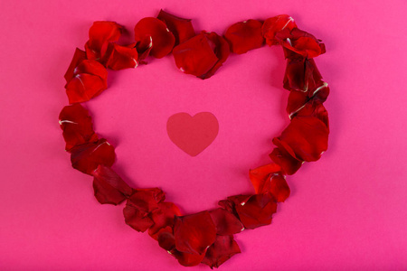 玫瑰花瓣的心脏在粉红色的背景与红色纸板心脏里面