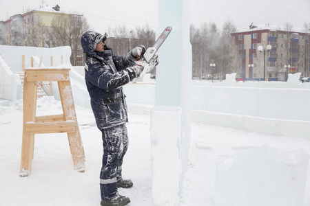 雕塑家在圣诞节用电锯把冰像从冰上剪下来