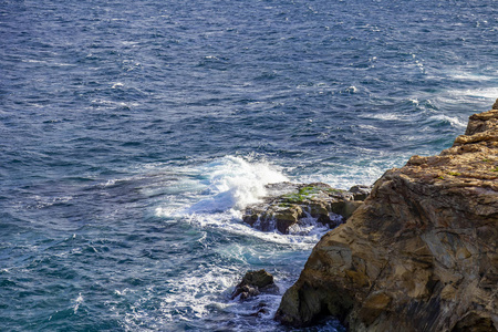 地中海岩石海岸附近有泡沫的如画的海浪，被黎明的太阳照亮