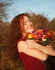 快乐的微笑的女人，带着鲜花在户外。