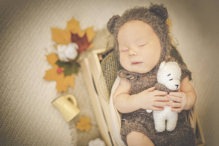 一个新生睡觉的男孩在熊的服装的肖像