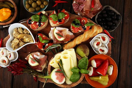 意大利反帕斯蒂葡萄酒小吃一套。 奶酪品种，地中海橄榄，咸菜，火腿，西红柿，洋蓟在桌子上。