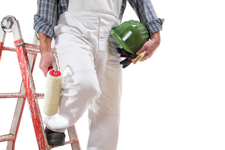 梯子和滚子房子油漆工人在梯子上穿着白色的工作服,把滚筒放在手里
