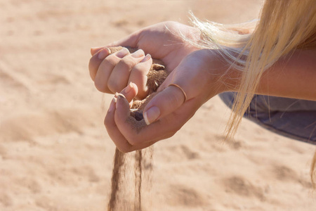 女孩手里拿着沙子,沙子从手指里流过照片