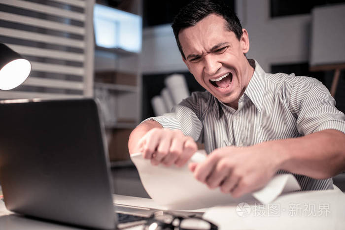 愤怒的不幸的人撕下一张纸
