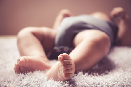 新生亚洲婴儿睡在白色毛茸茸的布上的脚