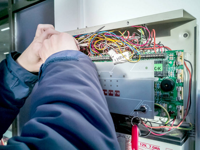 一名合格的工程师在电气面板中工作.维修高压设备的工人照片