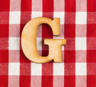字母表G字母红色格子织物桌布。