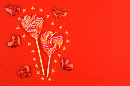 红色背景上两颗心形糖果。围绕着糖果，星星和红心。