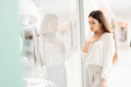 购物中心的女人。女孩站在商店橱窗边看新衣服