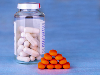 一组红色医疗药丸和一瓶白色药丸在蓝色背景上