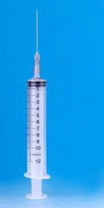 医用塑料注射器，针头在蓝色背景上充满液体。 治疗概念。