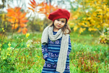 大自然中一个小女孩的肖像。 穿着红色贝雷帽和保暖毛衣的婴儿