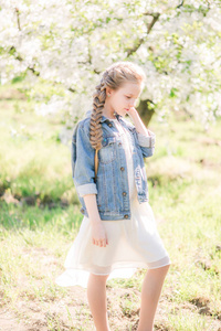 春天，在郁郁葱葱的花园里，一个金发碧眼的可爱女孩穿着白色的太阳裙
