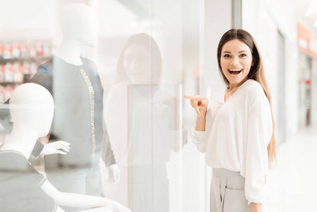 购物中心的女人。女孩站在商店橱窗边看新衣服