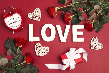 情人节背景与文字爱情玫瑰花闹钟礼物和装饰心上的红色。 自上而下的构图。