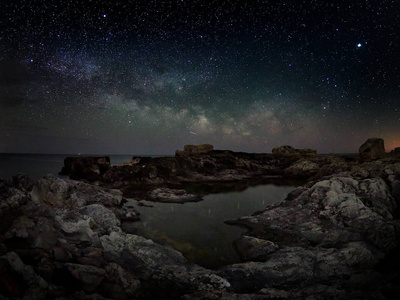 在岩石悬崖和海夜景观上令人叹为观止的充满活力的银河形象