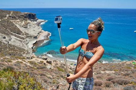 夏季地中海沿岸带Gopro摄像机的年轻女子