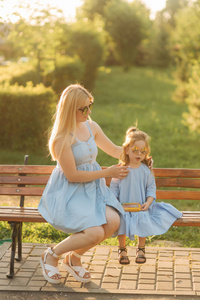 妈妈和他的小女儿坐在公园的长凳上。