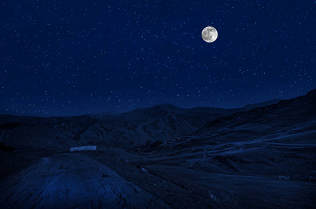 满月之夜，山路穿过森林。 夜晚风景优美的乡村道路，有大月亮