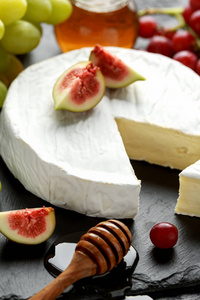 石板上的白色奶酪布与无花果, 绿色和红色的葡萄和蜂蜜