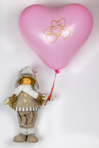 娃娃女孩穿着冬天的衣服，有一个粉红色的心球。 白色背景图像树假日爱心情人节复制空间。