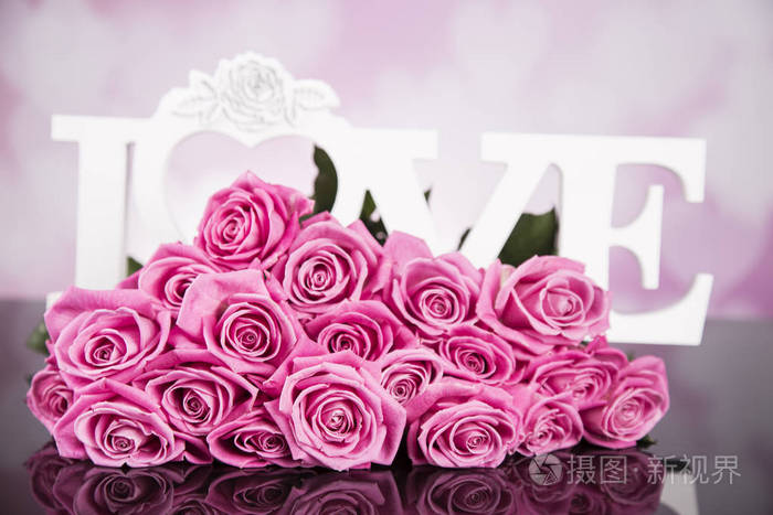 黑色背景上的一束粉红色玫瑰，上面写着爱。
