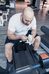 跑步运动员在健身房里放松地在驾驶机器上吃冰淇淋
