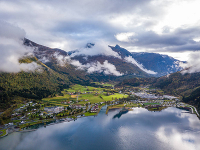 无人驾驶飞机照片的里昂在挪威的城市景观与Innvikfjorden峡湾在前景和云层覆盖大山的背景概念的旅行和和谐。