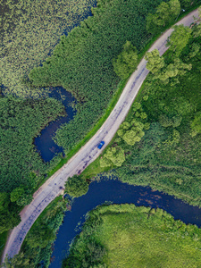 空中摄影汽车在河边行驶的道路上，在树下自上而下地观看乡村和谐自由的和平生活理念