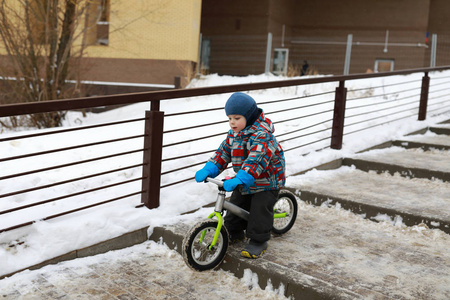 冬天，孩子们骑着平衡自行车下楼