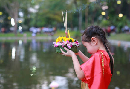 洛伊克拉通节日亚洲女孩穿着泰国传统服装，手持克拉通宽恕女神恒河在泰国庆祝节日。