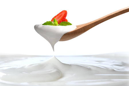 纯酸奶放在勺子上，上面挂着新鲜草莓，纯酸奶放在白色背景上