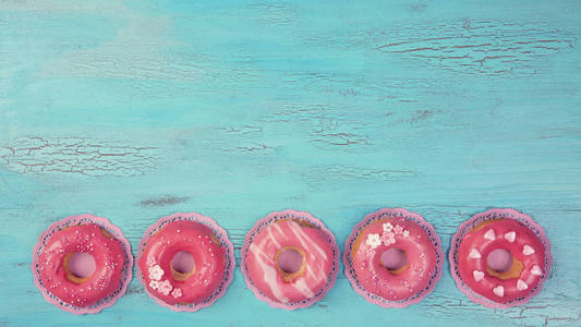 蓝色木制背景上的粉红色甜甜圈图片
