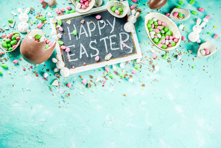 彩色的春天复活节糖果背景与巧克力鸡蛋，糖洒和棉花糖兔子绿松石，浅蓝色混凝土背景复制空间顶部视图